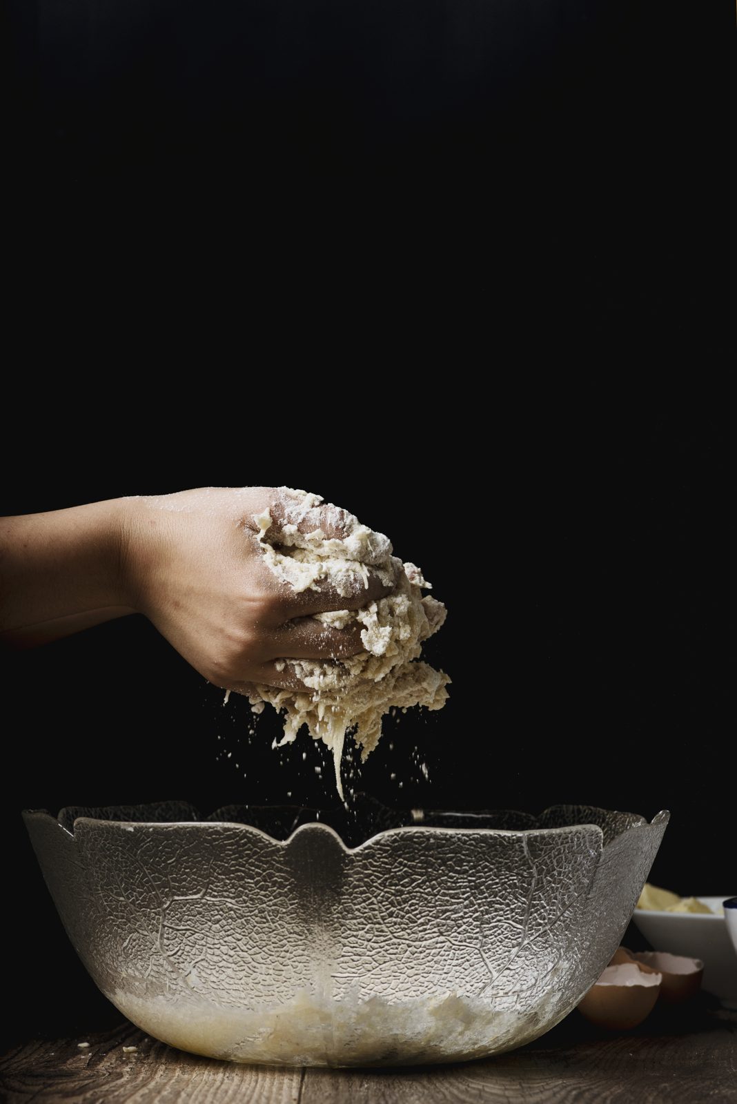 Hands sifting flour over a mixing bowl