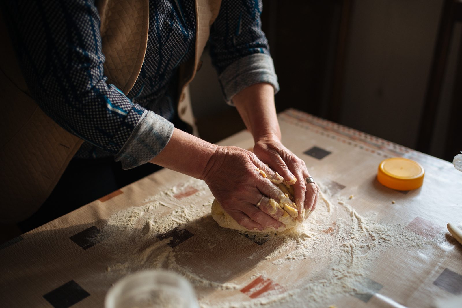 Baker's hands kneading dough on a floured counter